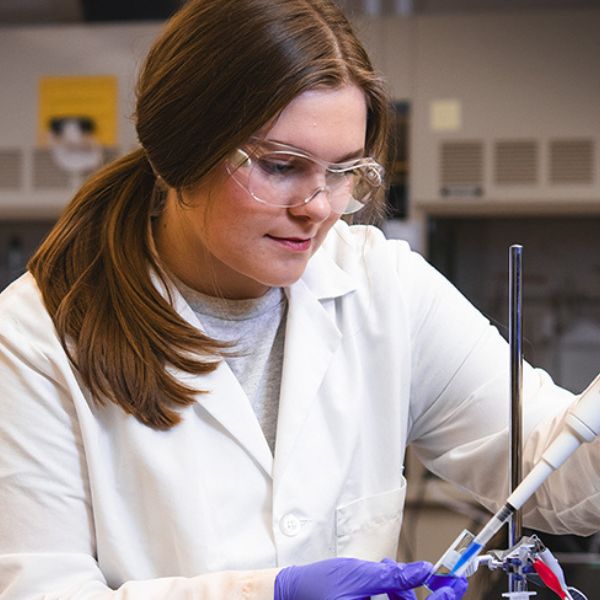 Sydney Erin Frenk works in lab with labcoat and safety glasses