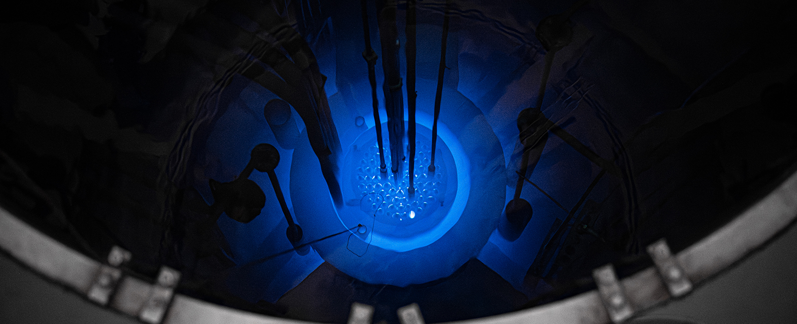 A topdown view shows a glowing blue nuclear reactor under a pool of dark water.