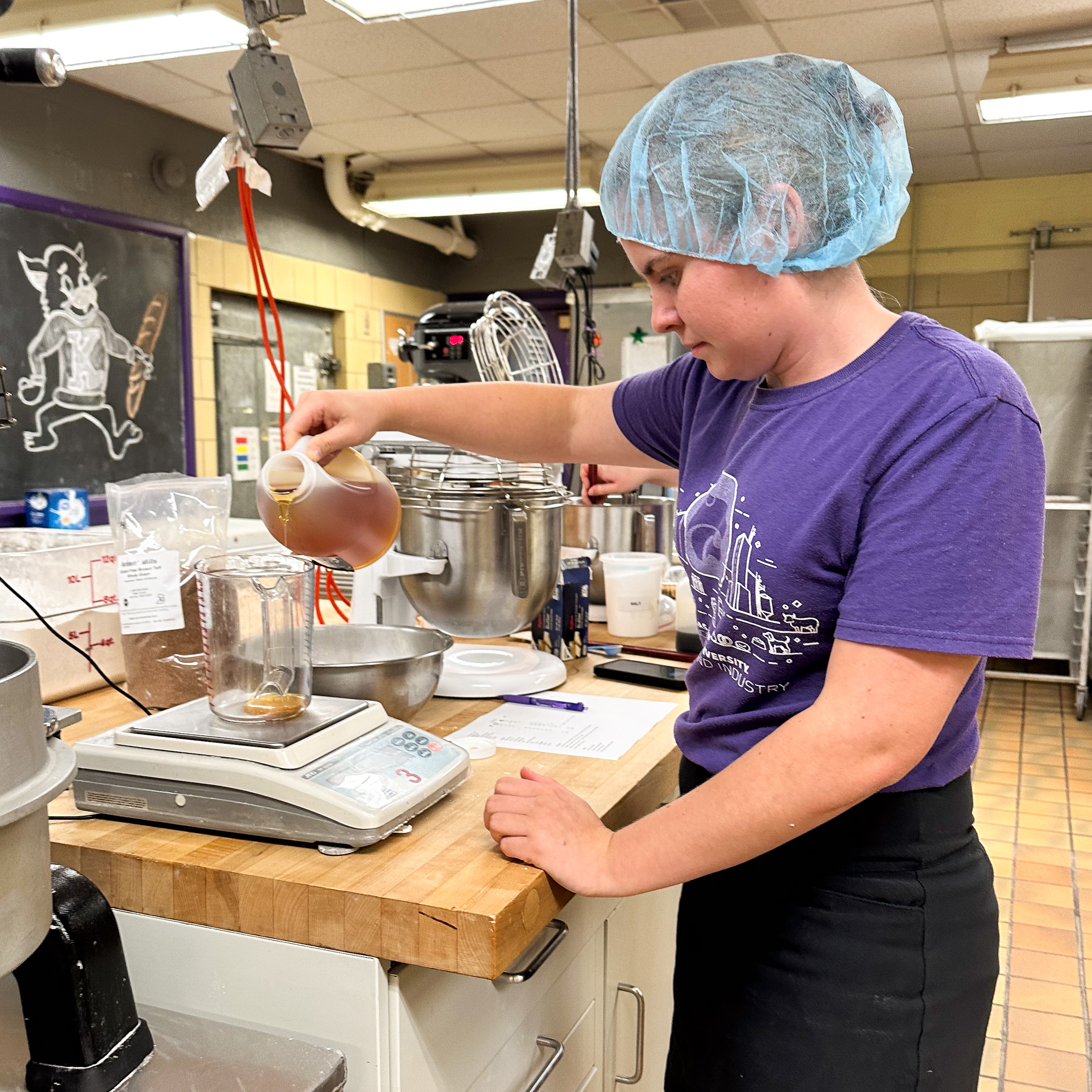 A K-State student measures honey in a kitchen. 