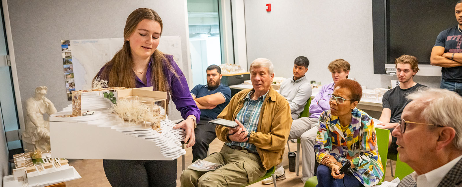 Student showcasing architecture model to faculty