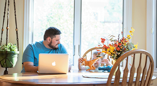 A man completes online learning at K-State from his kitchen table