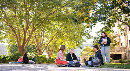 Students sit outside in Bosco Plaza