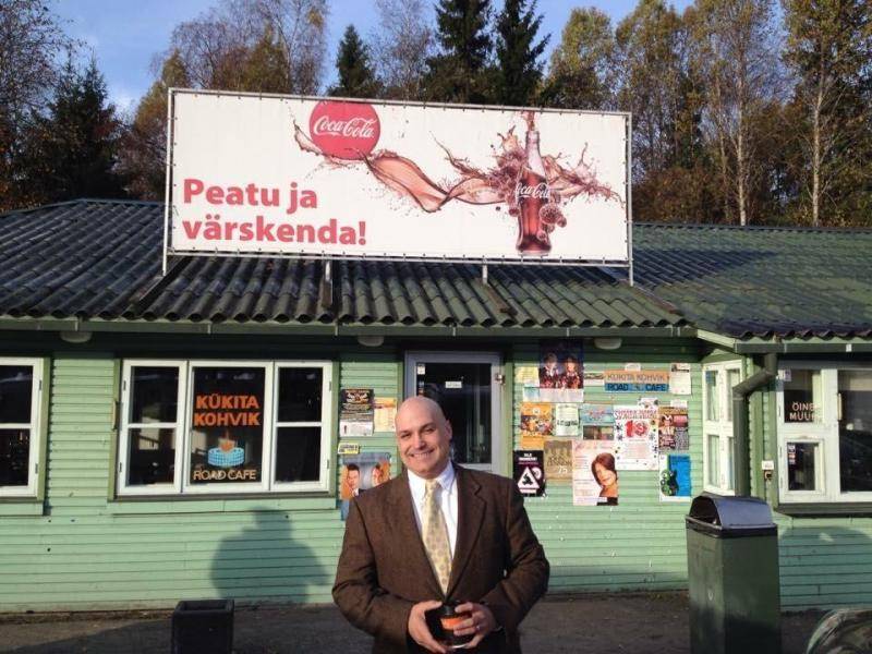 Picture of Dr. Scott Mcintosh standing in front of a green building and a white and red Coca-Cola sign with Russian text
