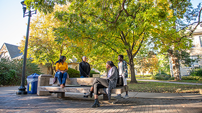 group of students sitting on benches outside of Anderson Hall