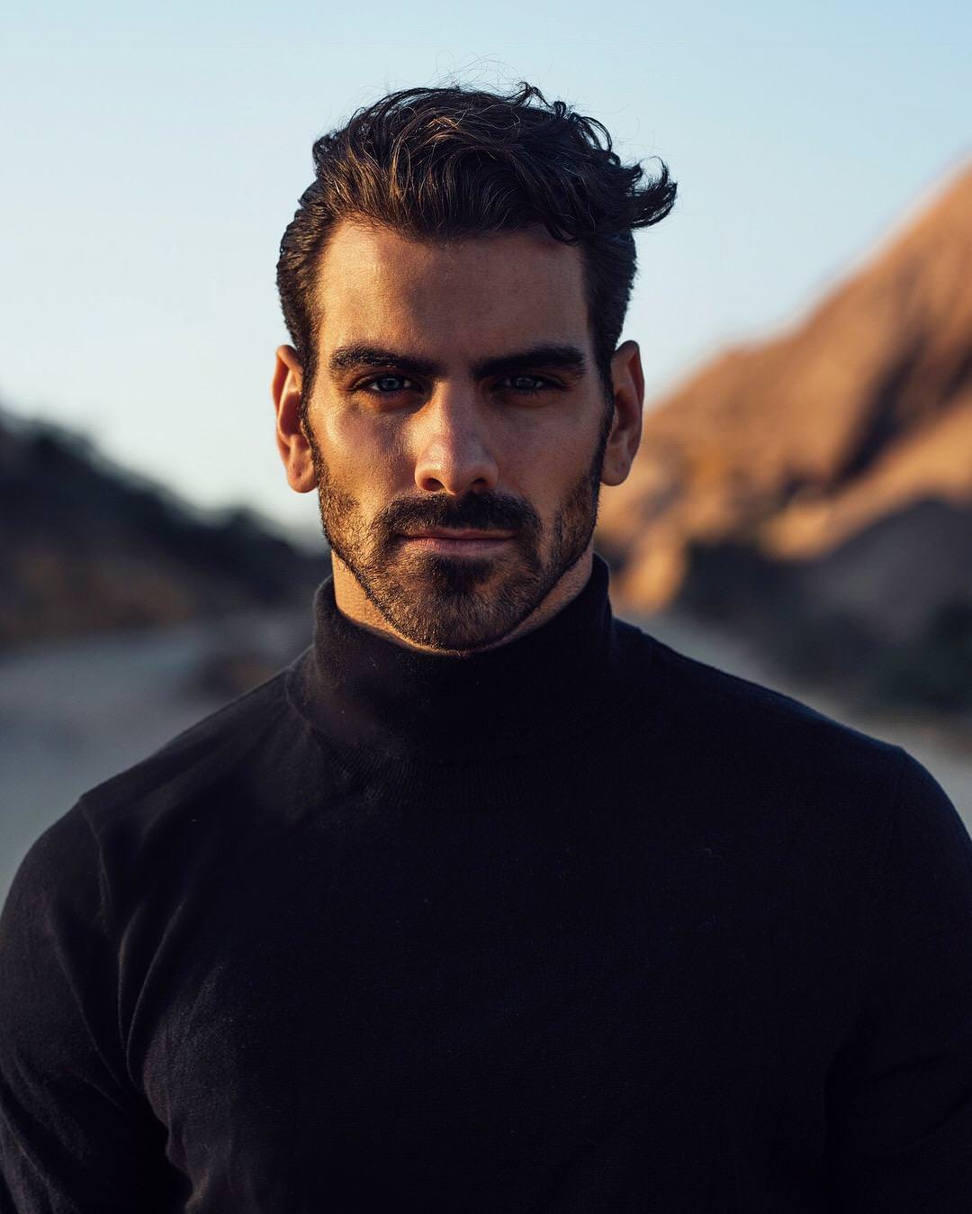 Nyle DiMarco looking at the viewer with mountains behind him