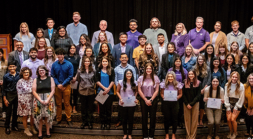 Tri-alpha inductees stand on the stage.