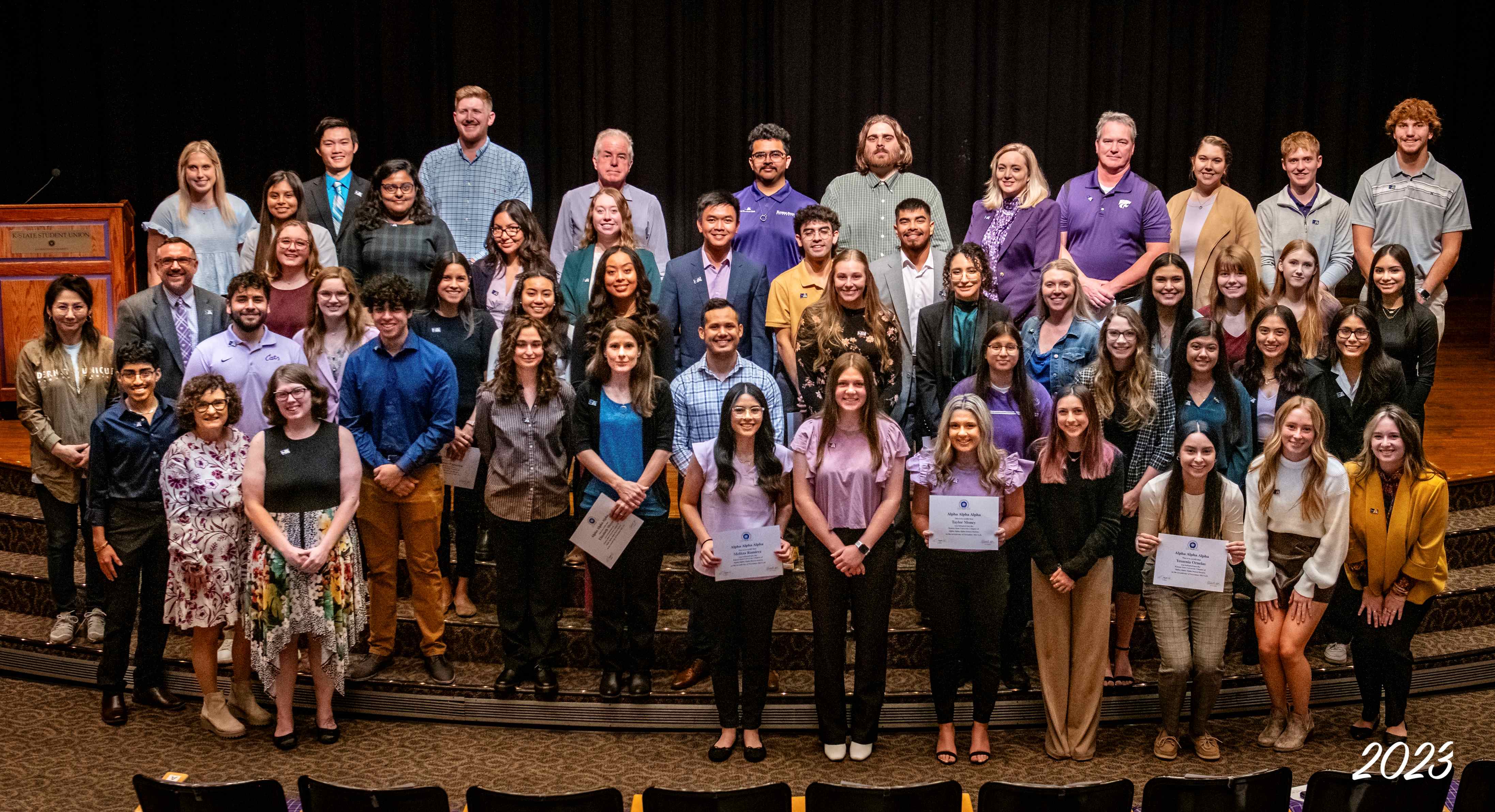 Large group of students standing on steps holding Tri-Alpha certificates.