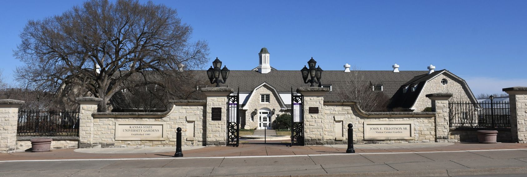 view looking through stone gates across a fountain onto the front of the limestone gardens visitor center and old dairy barn