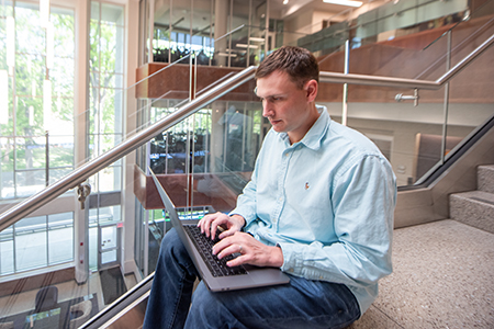 man sitting on steps with a laptop