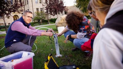 Instructor and students with lab equipment outdoors