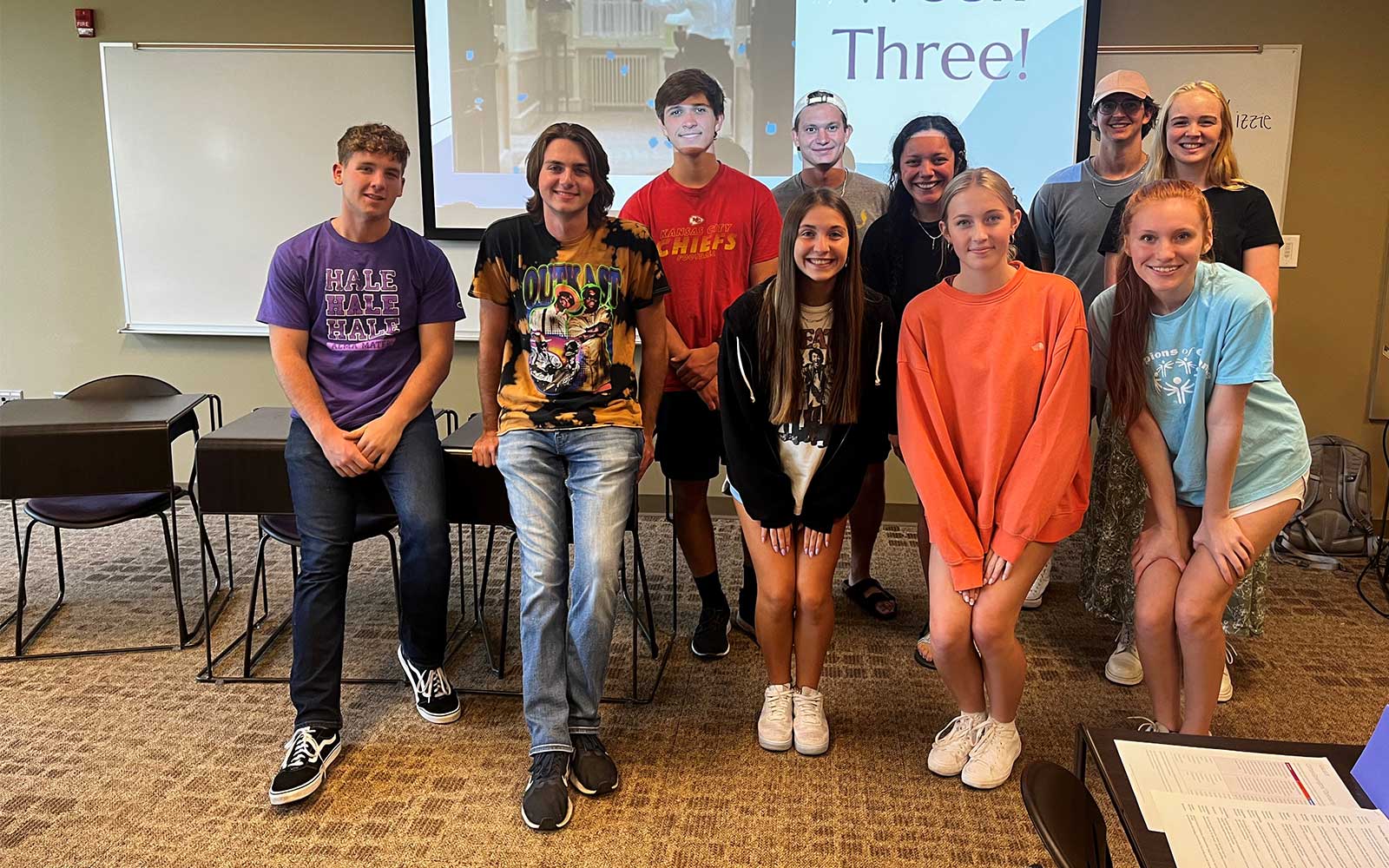 A class leader poses for a photo with their group of LEAD 212 students in a classroom.