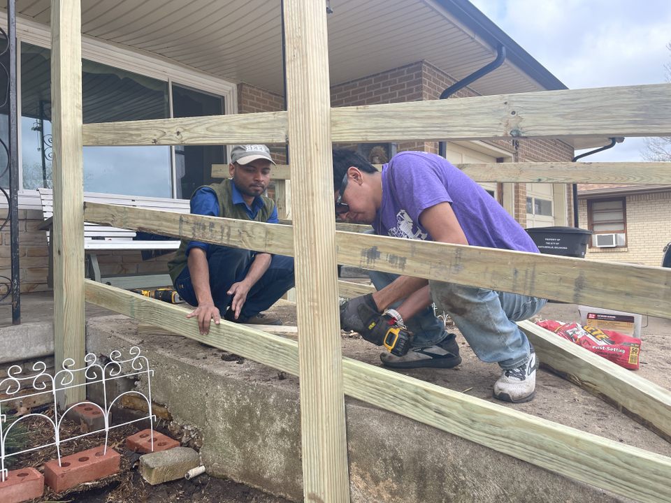 Two people work to build a wooden ramp for a home