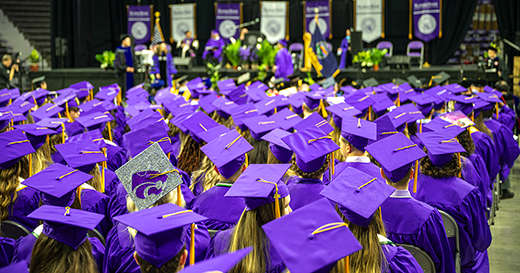 A group of seated graduates in purple caps and gowns