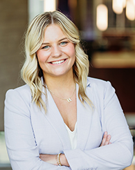 A student with blonde hair and a lavender blazer.