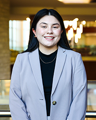 A student in a blazer smiling for a portrait photo.