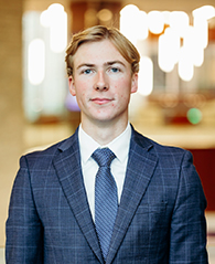 A student in a suit smiling for a portrait photo.