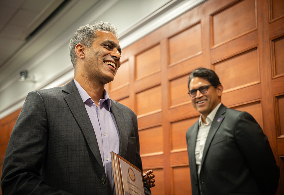 A man walks in front of another man as he goes to accept his award. 