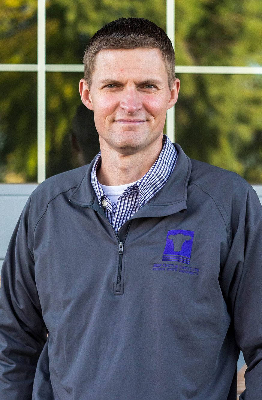 A man smiles for a photo in front of a window.