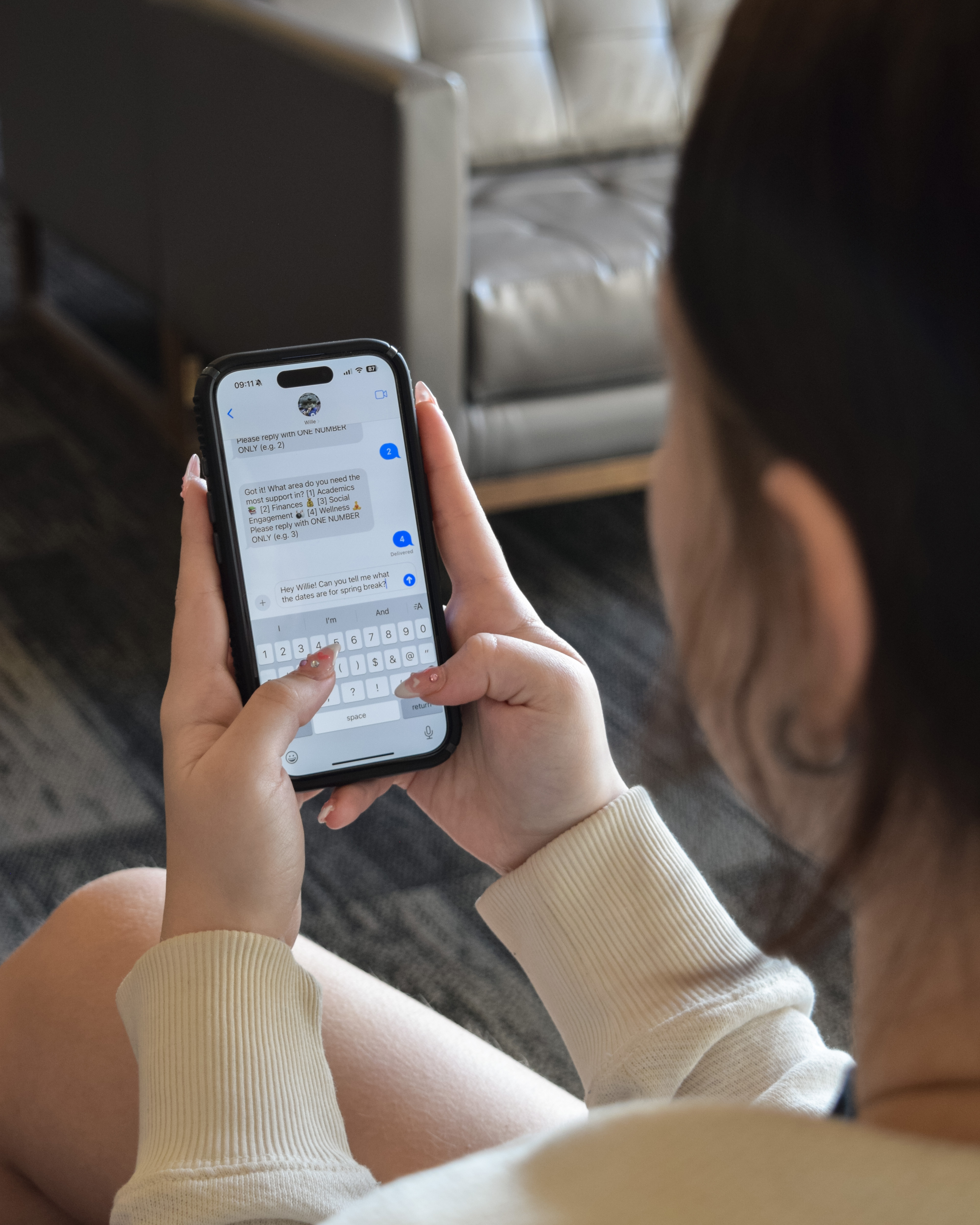 A closeup of a phone screen shows a student texting and having a conversation with a virtual assistant named Willie.