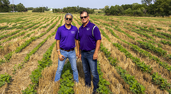 two men, one a farmer and one a K-state agricultural engineer stand together in a field 