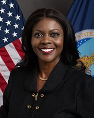 A Black woman in a suit in front of the U.S. flag