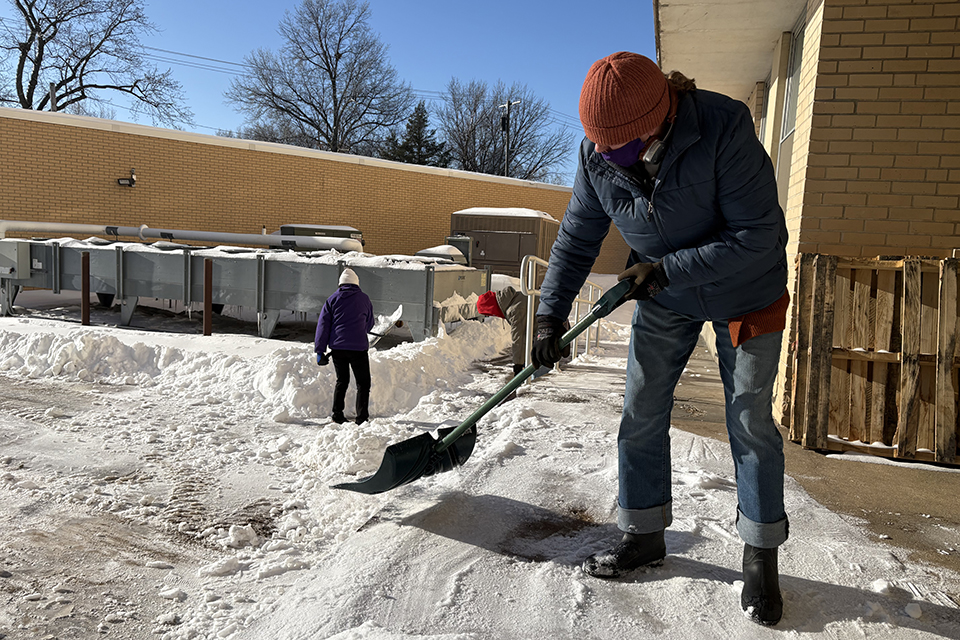 Melanie Coble, custodian, clears snow from the receiving dock at the Unger Complex.