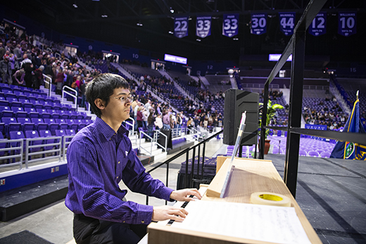 A student in a purple shirt plays the organ at fall 2023 commencement ceremonies in Kansas State University's Bramlage Coliseum.