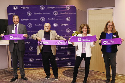 A group of university administrators hold up purple ribbons that were to be cut to formally launch the Biomedical Core Facilities in the College of Veterinary Medicine at Kansas State University.