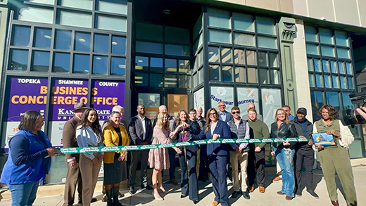 A group of people standing in front of a building cutting a ribbon