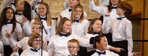 children in formal performance attire singing