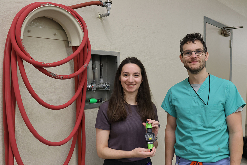 Gabrielle Maroulis and faculty research mentor Nathaniel Kapaldo hold a water meter. 