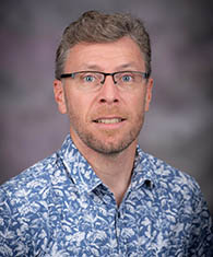 A man in glasses and a blue button-down shirt.