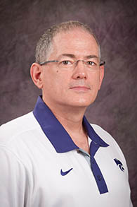 A man in glasses and a white polo with a purple powercat on it.