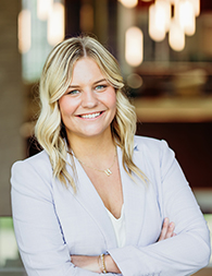 A young woman with blonde hair in a white blazer.