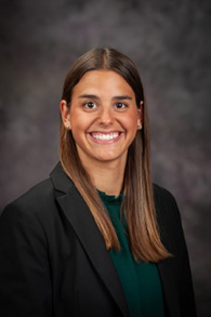 A young woman in a green shirt and black blazer.