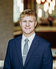 A young man with blonde hair and a navy blazer.