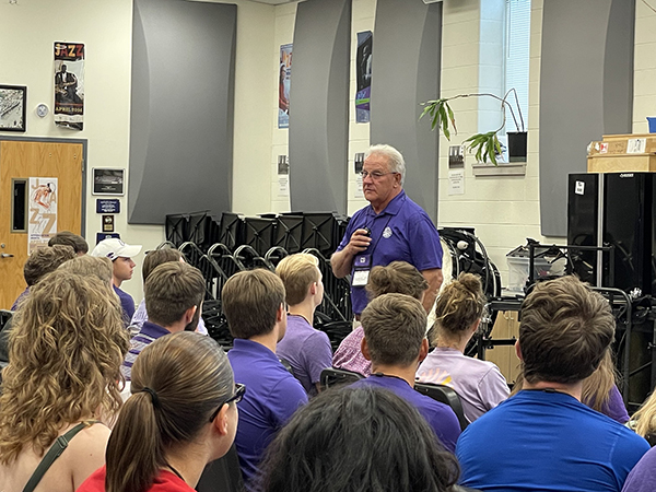 Frank Tracz, director of bands, speaks in front of a group of marching band students