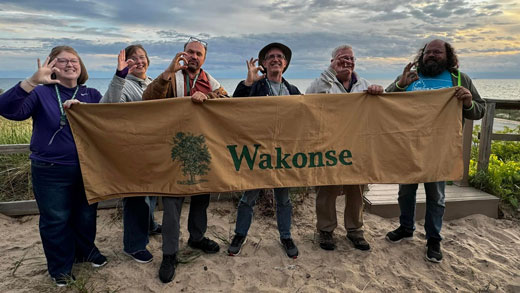 K-State faculty members stand with a "Wakonse" banner at the Wakonse Fellowship 34th annual conference at Camp Miniwanca on Lake Michigan. 
