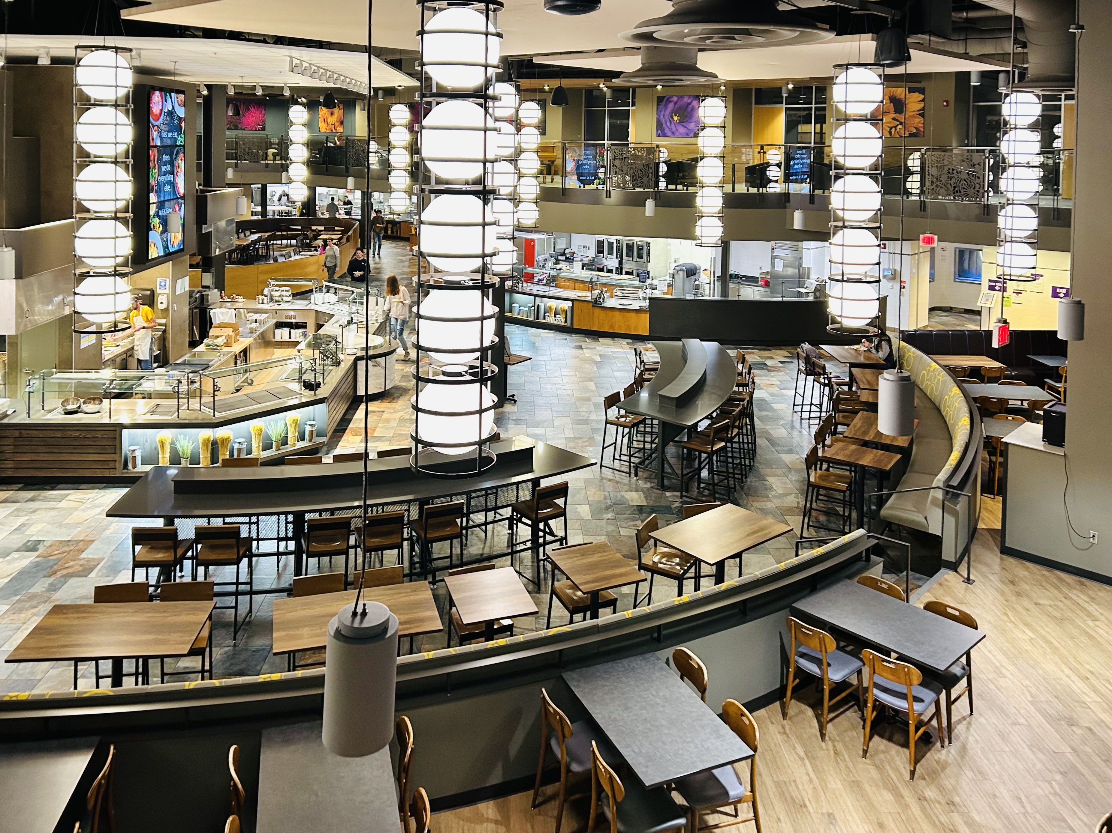 Derby Dining Center's showcases what thoughtful design brings to k-state, the modern design of globe lights hanging from the ceiling and dark wood tables paired with easily accessible and inviting food counters prioritize the student experience