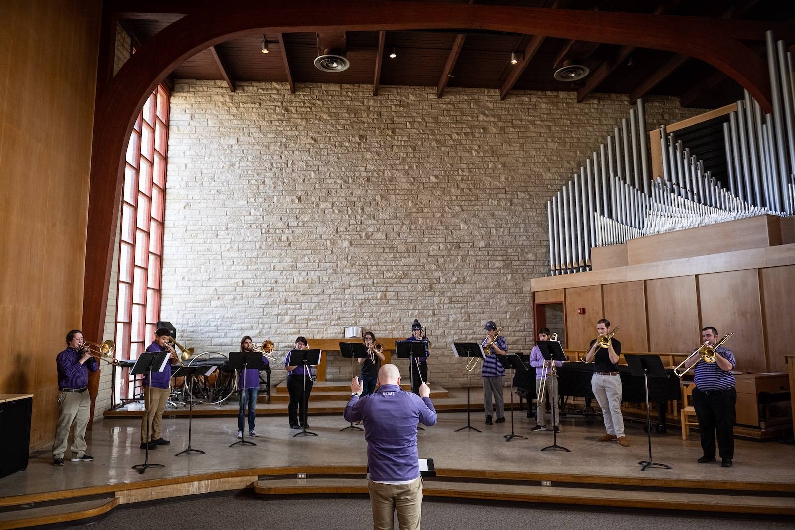 trombone players stand across the front of a stage