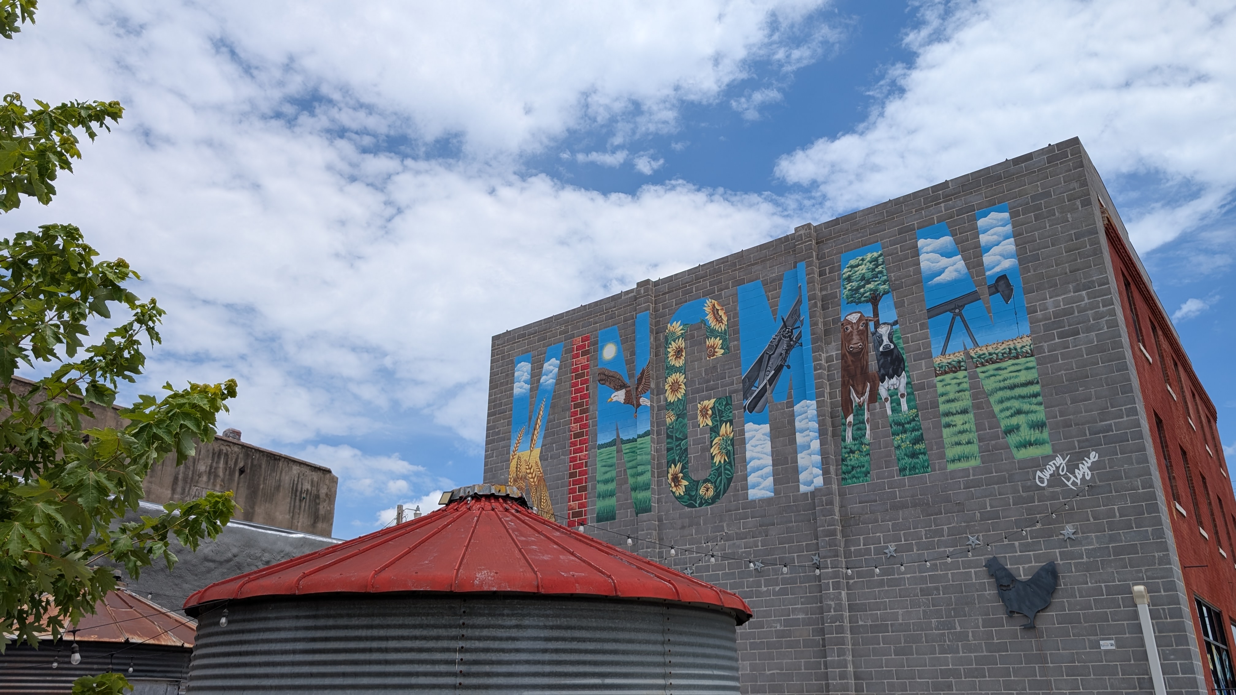 A brick building against a blue sky with decoratively painted letters that spell KINGMAN.