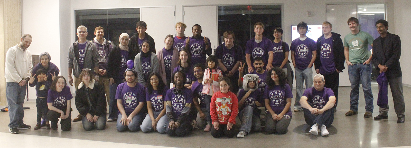 K-5 hour of code participants pose with K-State computer science students and station leader volunteers.