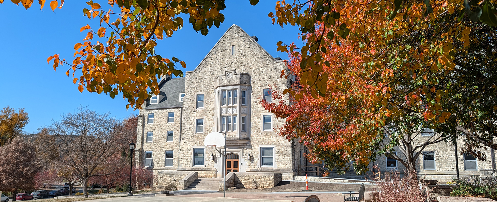 An exterior shot shows a limestone college residence hall in the autumn.