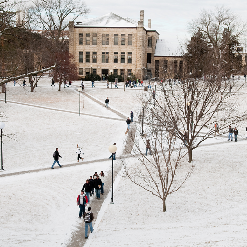 An aerial shot shows students walking across a snowy campus.