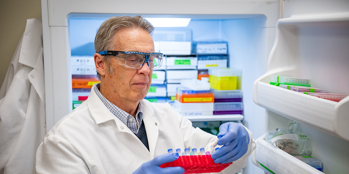 James Stack stands in a laboratory at Kansas State University’s Biosecurity Research Institute wearing a white lab coat.