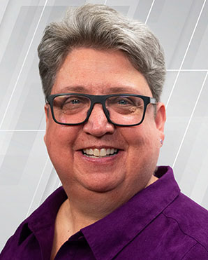 A woman in a purple shirt smiles for a portrait.