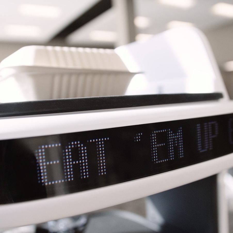 A close-up of the Lacy's food delivery robot displays the message 