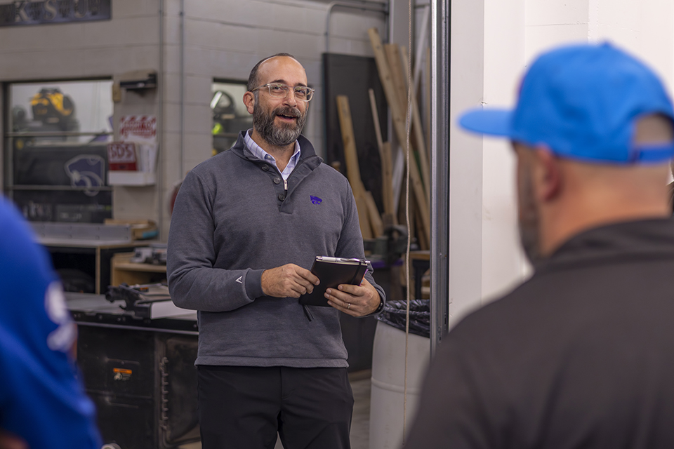 A college professor stands in front of a group and discusses the research laboratory they're in.