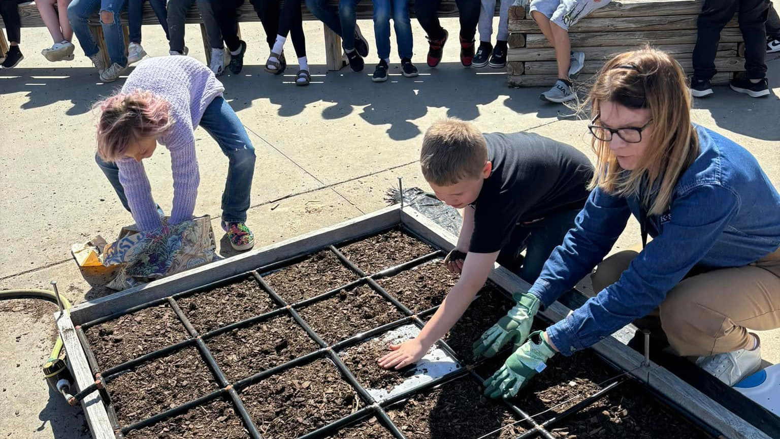 A college professor sits and looks at a presentation off-screen next to one of her students.