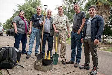 A group of veterinary researchers wearing casual clothing pose for a portrait on a street in South Africa.